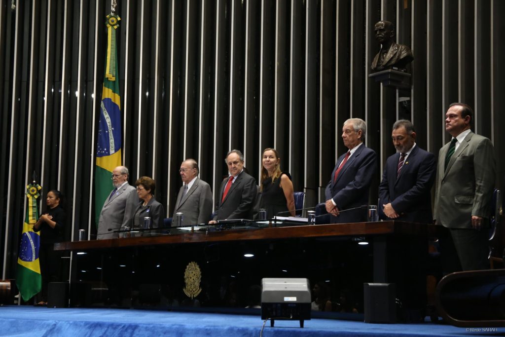 Dra. Lúcia Willadino Braga em pé junto as outras autoridades durante a execução do hino nacional