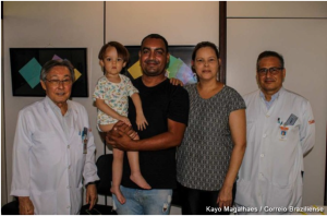No ambulatório do SARAH Brasília, à esquerda, Dr. Álvaro Massao Nomura, ortopedista e vice-presidente da Rede SARAH, posa para foto com pais de paciente paciente infantil e com o ortopedista Oton Lima. Os médicos trajam jalecos do hospital.