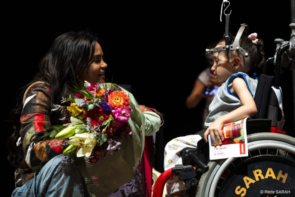 A paciente Ana Liz de Jesus Pádua Lima entregando um buquê de flores a Lucy Alves.